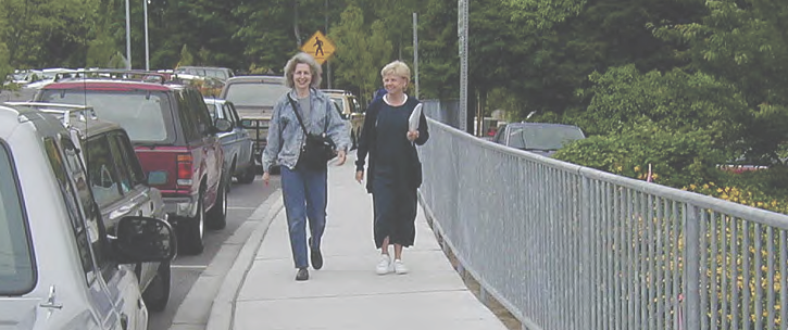Two women walking on sidewalk.