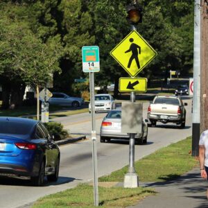 Pedestrian crosswalk sign with traffic in Polk County reminding drivers to yield and promote safer walking during Pedestrian Safety Month.
